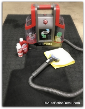 A Hoover carpet cleaning machine sitting on top of a floor mat from a black interior of a BMW M4 Carpet cleaning machine versus steam cleaner