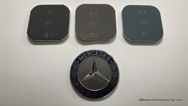 Turtle Wax clear coat scratch remover sanding discs sitting on hood of white Mercedes Turtle Wax clear coat scratch remover sanding discs