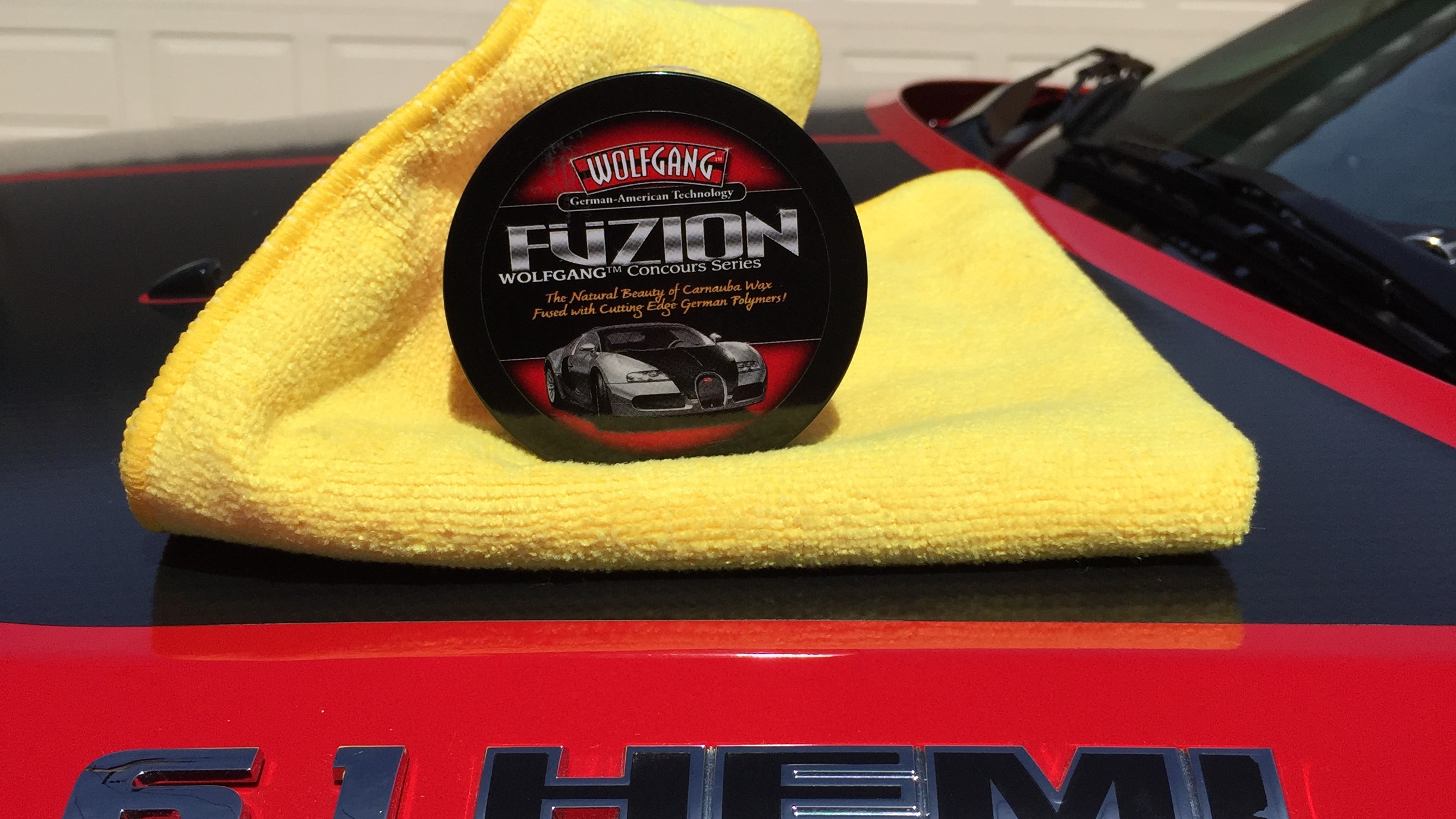 Fuzion car wax sitting on top of the hood of a Dodge SRT wax to remove swirl marks on car